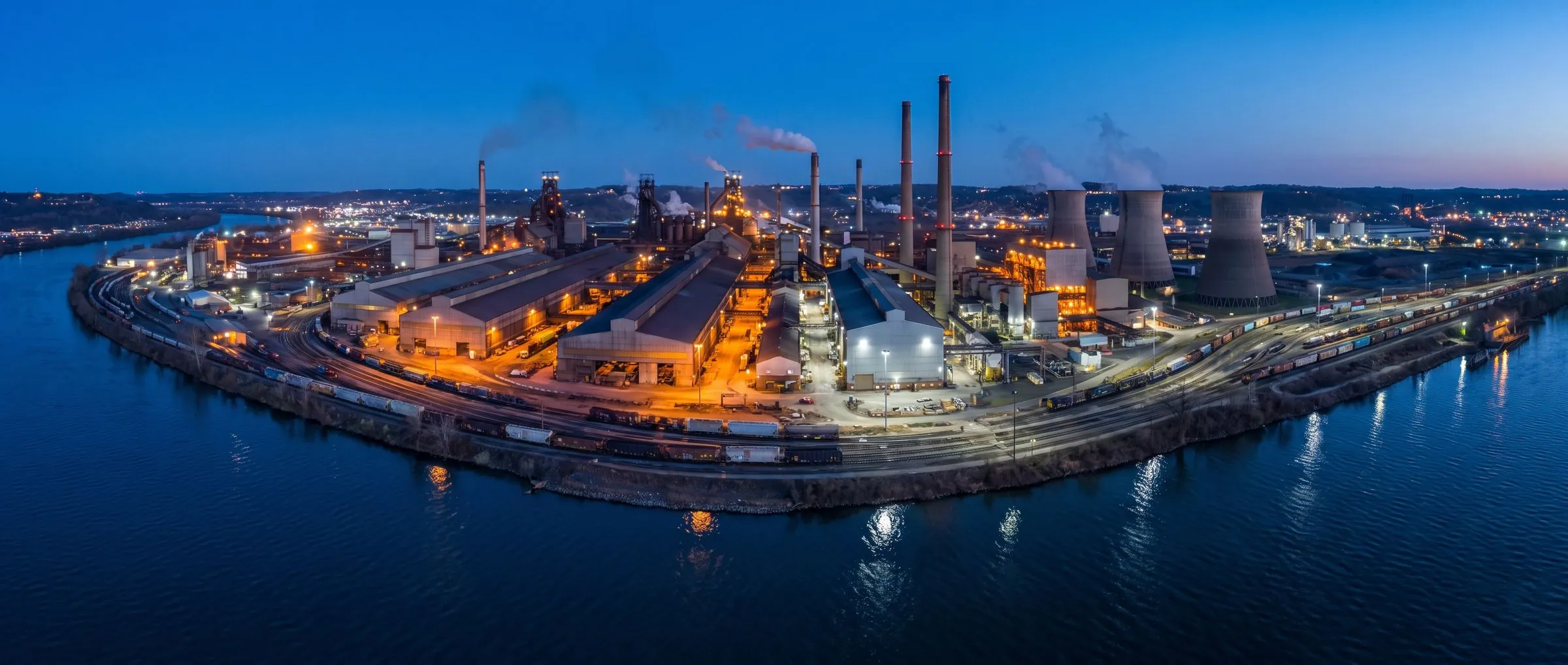 Aerial view of a steel plant on a riverbank at blue hour